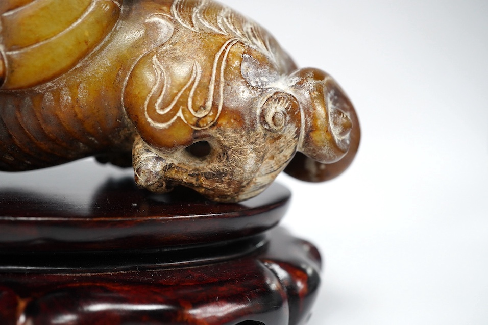 A Chinese archaistic pale celadon russet and burnt jade figure of a winged mythical beast, wood stand, mythical beast 12cm wide. Condition - carving good, stand good
